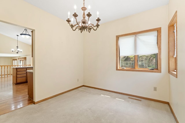 unfurnished room featuring a chandelier, light colored carpet, and baseboards