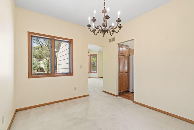 unfurnished room featuring light colored carpet, a chandelier, and baseboards