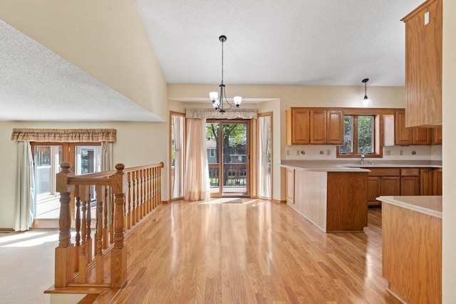 kitchen featuring light wood-style floors, light countertops, a textured ceiling, pendant lighting, and a peninsula