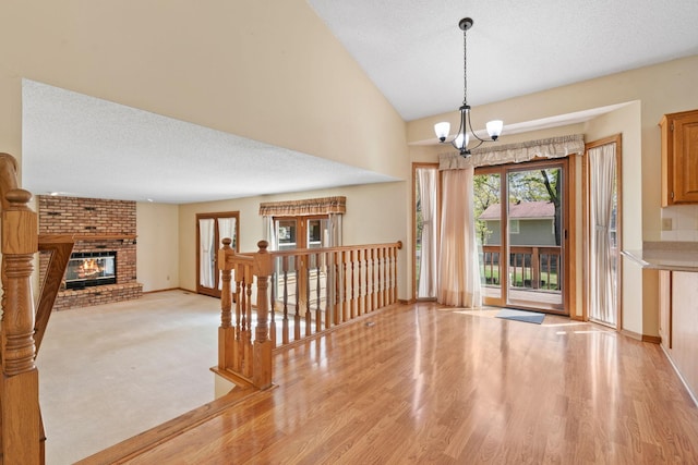 entrance foyer with a chandelier, baseboards, light wood finished floors, a fireplace, and a textured ceiling
