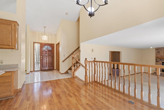 foyer with a chandelier, light wood finished floors, baseboards, a high ceiling, and stairs