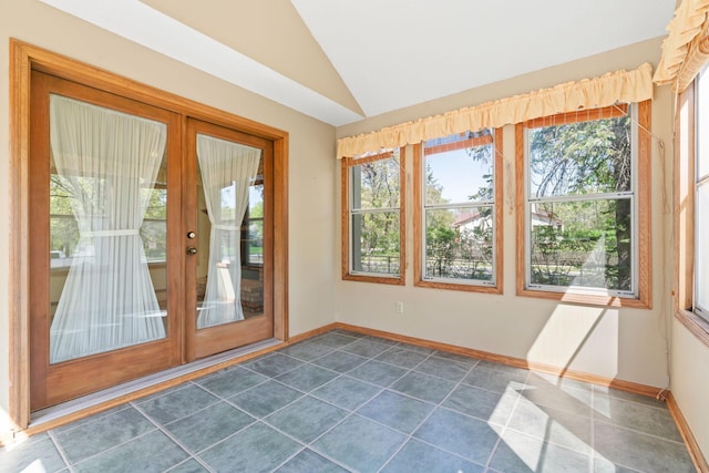 doorway to outside featuring vaulted ceiling, healthy amount of natural light, baseboards, and dark tile patterned floors