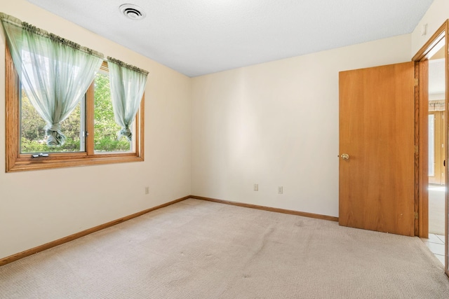 empty room featuring light carpet and baseboards