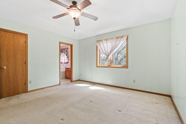 unfurnished bedroom with light colored carpet, baseboards, ensuite bath, and ceiling fan