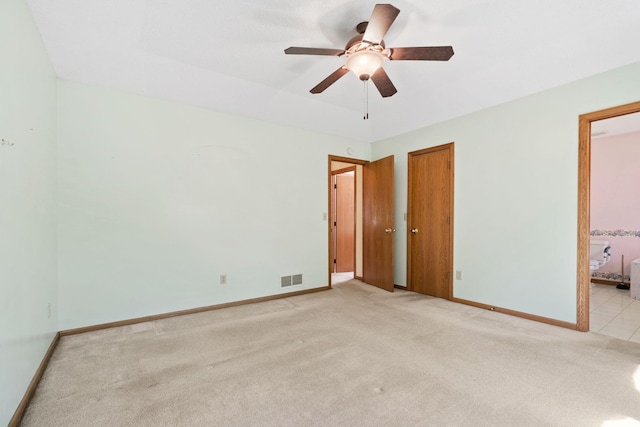 unfurnished bedroom featuring light carpet, baseboards, connected bathroom, and a ceiling fan