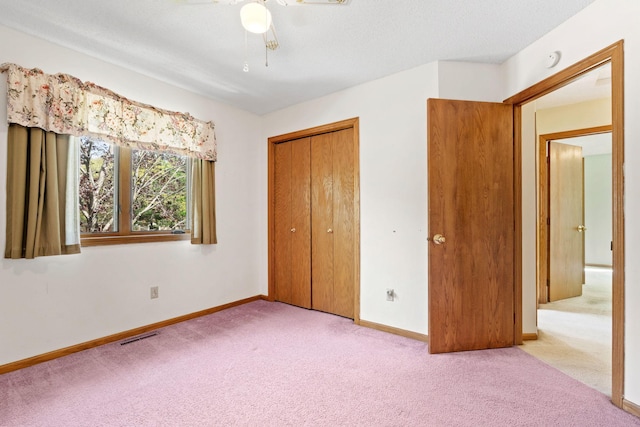 unfurnished bedroom with carpet flooring, baseboards, a closet, and a ceiling fan