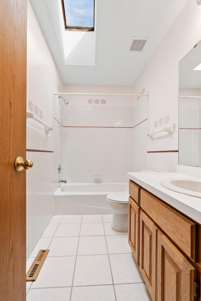 bathroom featuring tile patterned flooring, a skylight, toilet, tub / shower combination, and vanity