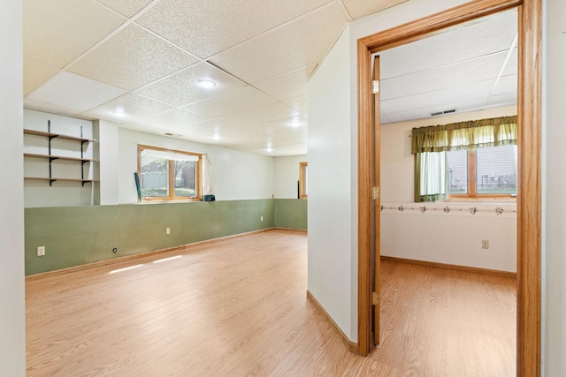 below grade area featuring a drop ceiling, wood finished floors, and baseboards