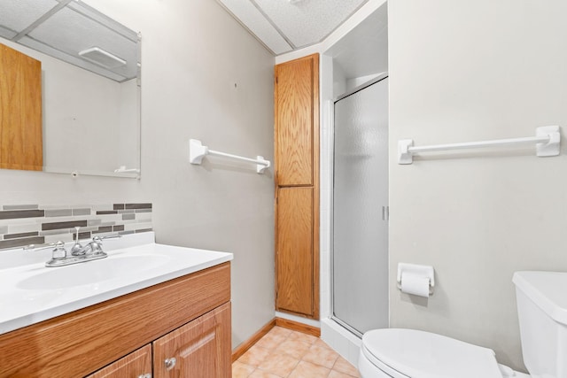 bathroom with toilet, a shower stall, backsplash, vanity, and tile patterned floors