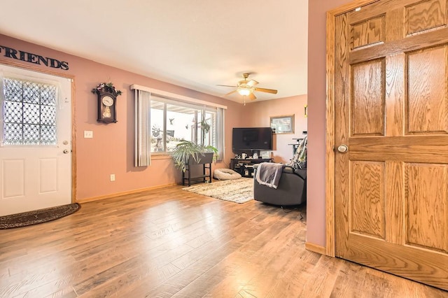 living room featuring baseboards, light wood finished floors, and ceiling fan