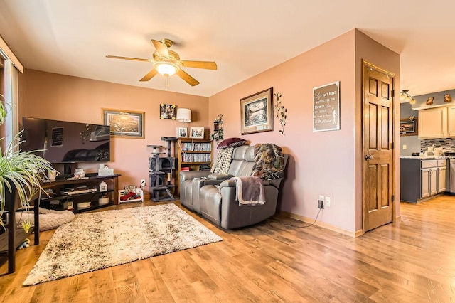 living area featuring light wood-style flooring, baseboards, and ceiling fan