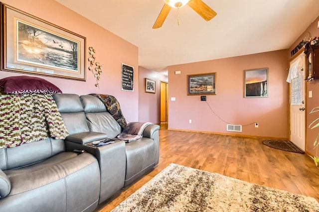 living room with baseboards, visible vents, light wood-style floors, and ceiling fan