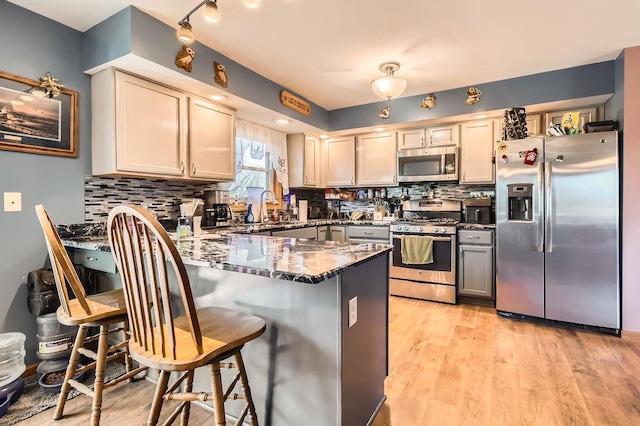 kitchen featuring a peninsula, appliances with stainless steel finishes, dark stone countertops, and decorative backsplash