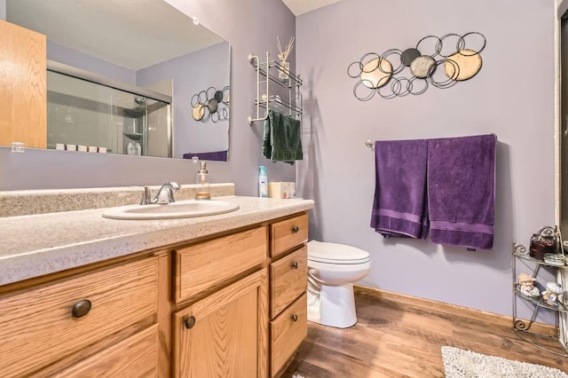 bathroom featuring toilet, vanity, a shower stall, and wood finished floors