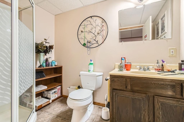 full bath with toilet, vanity, a stall shower, and a paneled ceiling