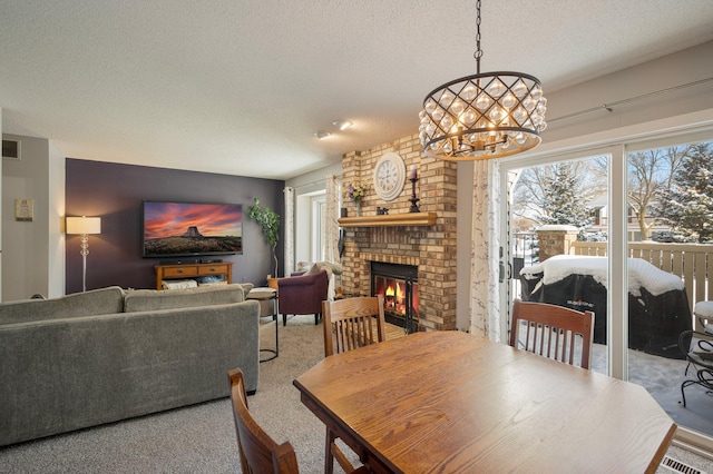 dining area with a textured ceiling, visible vents, a chandelier, a fireplace, and carpet floors