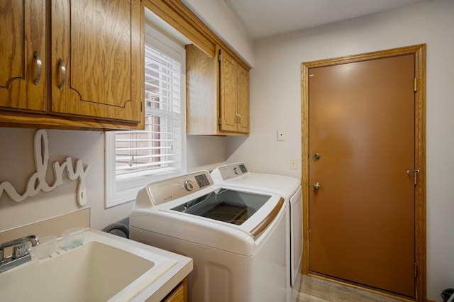 washroom with a sink, cabinet space, and washer and dryer