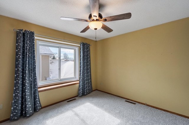 spare room with carpet flooring, baseboards, ceiling fan, and visible vents