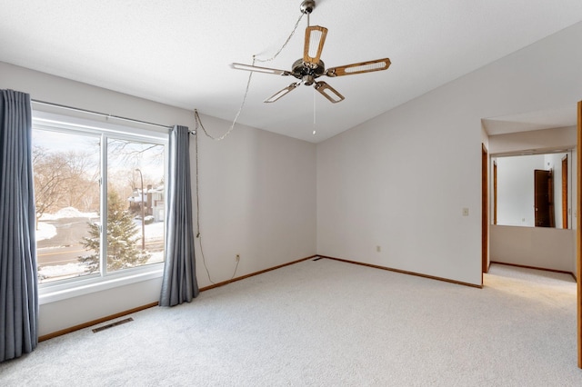 spare room with visible vents, baseboards, a ceiling fan, light carpet, and vaulted ceiling