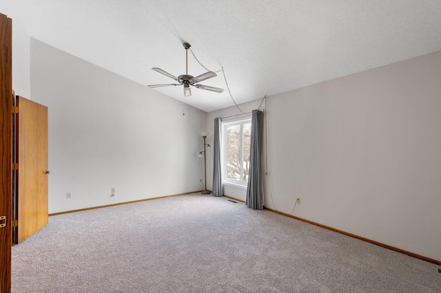 spare room featuring vaulted ceiling, light carpet, a textured ceiling, baseboards, and ceiling fan