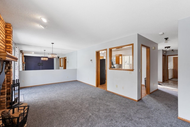 unfurnished living room with baseboards, a textured ceiling, carpet, and a brick fireplace