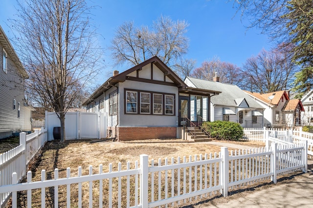 english style home featuring a fenced front yard, stucco siding, and a chimney