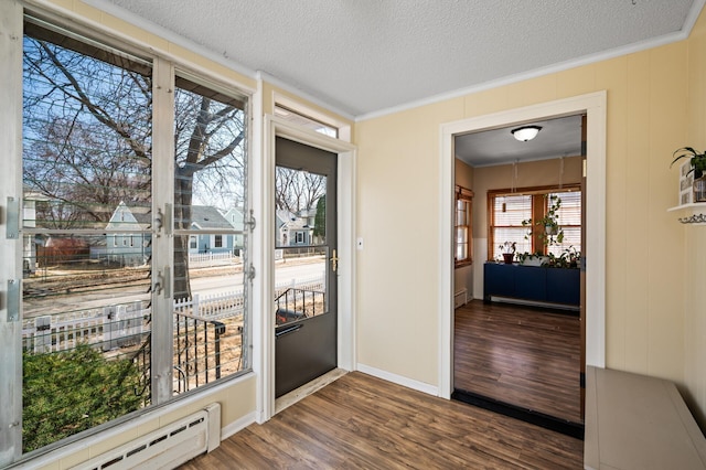 doorway featuring baseboards, ornamental molding, a baseboard heating unit, and dark wood-style floors