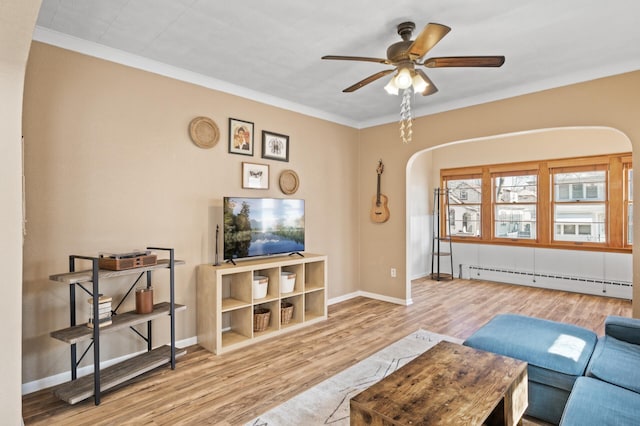living area featuring a ceiling fan, a baseboard radiator, arched walkways, and wood finished floors