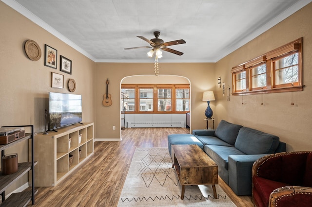 living area featuring crown molding, ceiling fan, wood finished floors, and a baseboard radiator