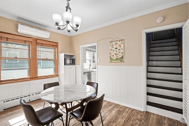 dining space featuring light wood finished floors, a wall mounted air conditioner, a chandelier, stairs, and a baseboard heating unit
