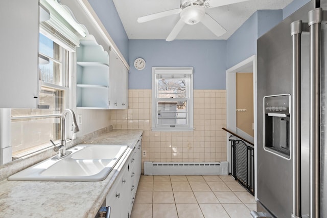 kitchen featuring stainless steel refrigerator with ice dispenser, a baseboard radiator, a sink, and plenty of natural light