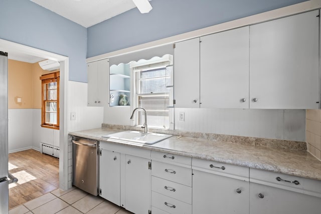 kitchen with stainless steel dishwasher, light countertops, a baseboard heating unit, a sink, and a wealth of natural light