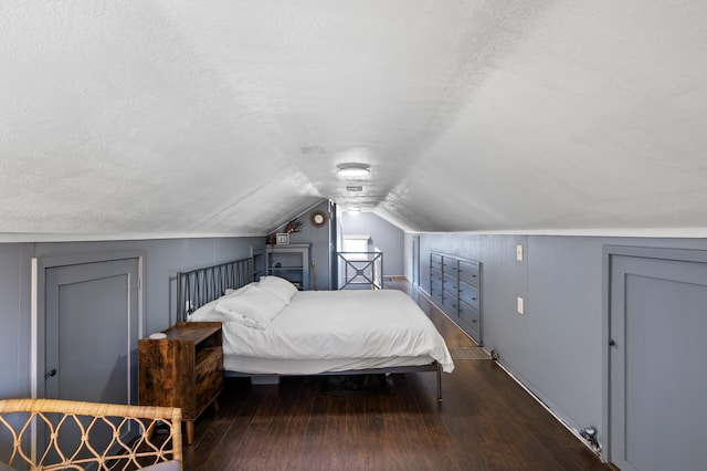 bedroom featuring baseboards, a textured ceiling, vaulted ceiling, and wood finished floors