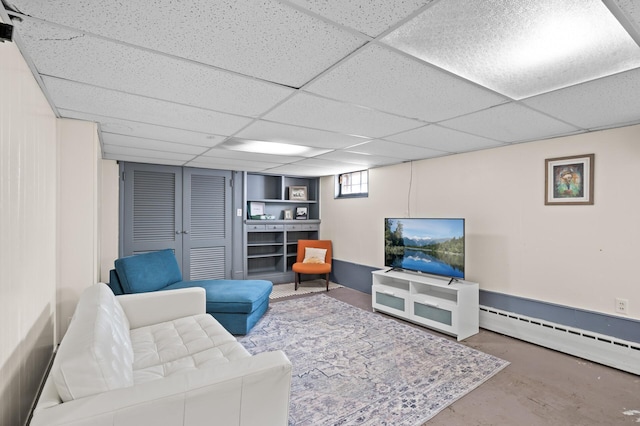 living room with a drop ceiling, concrete floors, and baseboard heating