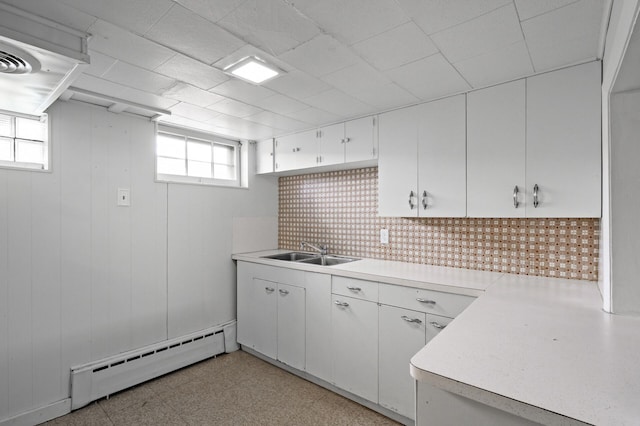 kitchen featuring white cabinets, a sink, baseboard heating, light countertops, and light floors