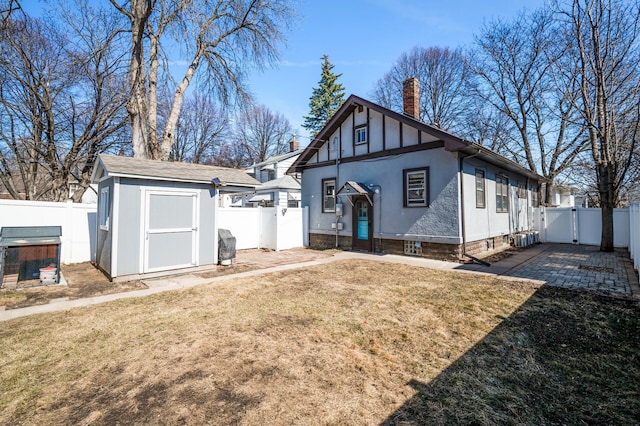exterior space with a fenced backyard, a shed, a yard, and a chimney