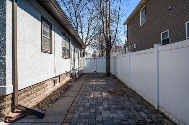 view of property exterior with a fenced backyard, a gate, cooling unit, and a patio area