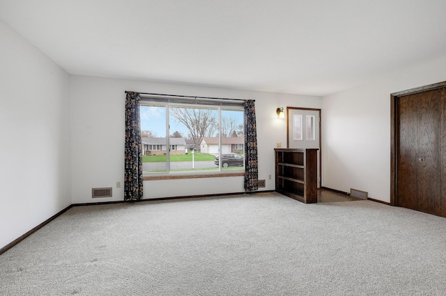 carpeted empty room featuring baseboards and visible vents