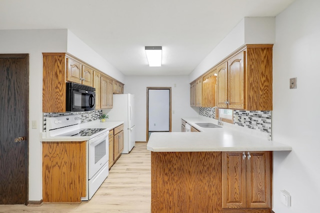 kitchen featuring black microwave, a sink, light wood-type flooring, backsplash, and white electric stove