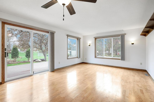 spare room featuring plenty of natural light, a ceiling fan, baseboards, and wood finished floors