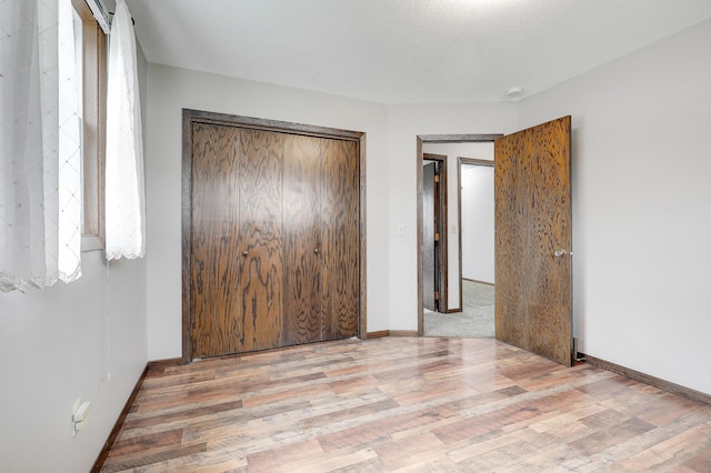 unfurnished bedroom featuring baseboards, a closet, and wood finished floors