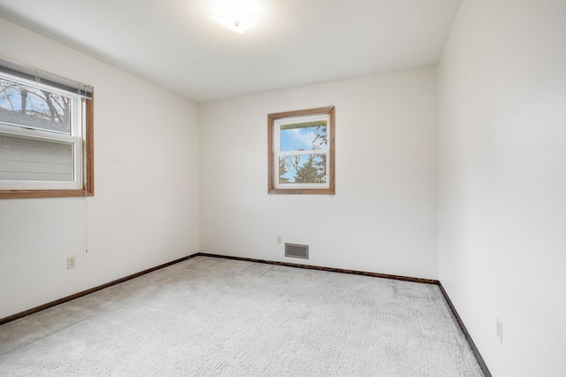 empty room featuring baseboards, visible vents, carpet, and a wealth of natural light