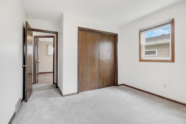 unfurnished bedroom with a closet, baseboards, and light carpet