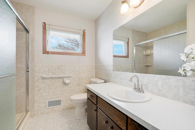 bathroom featuring tile walls, a wealth of natural light, a stall shower, and visible vents