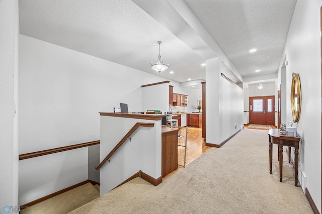 hall with a textured ceiling, baseboards, recessed lighting, an upstairs landing, and light colored carpet