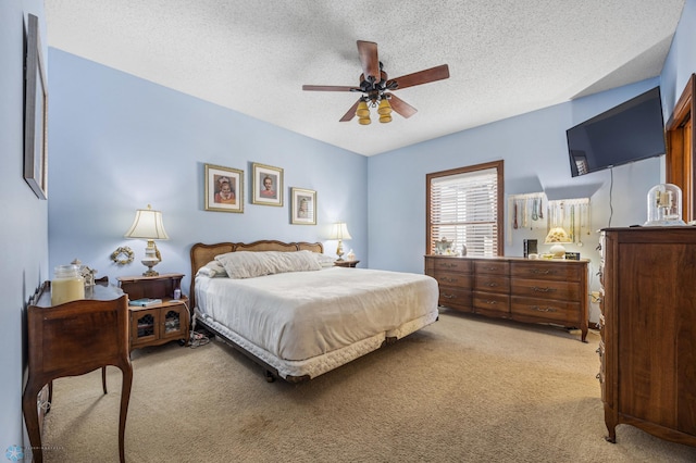 bedroom featuring light carpet, a textured ceiling, and ceiling fan