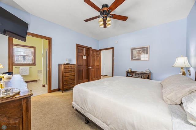 bedroom with light carpet, ensuite bath, and ceiling fan