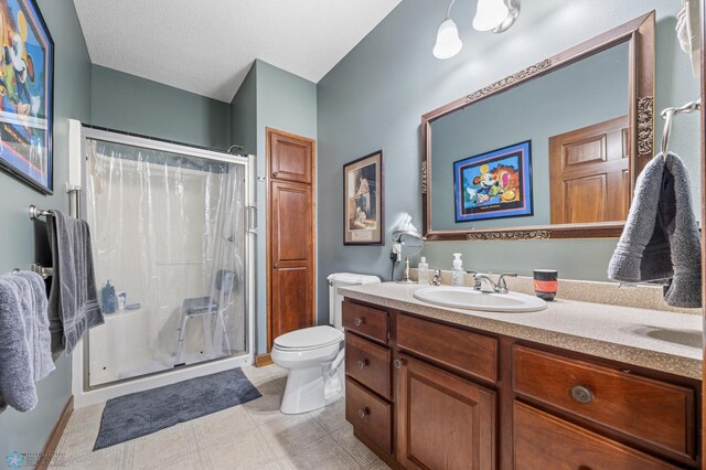 bathroom with baseboards, vanity, toilet, and a stall shower