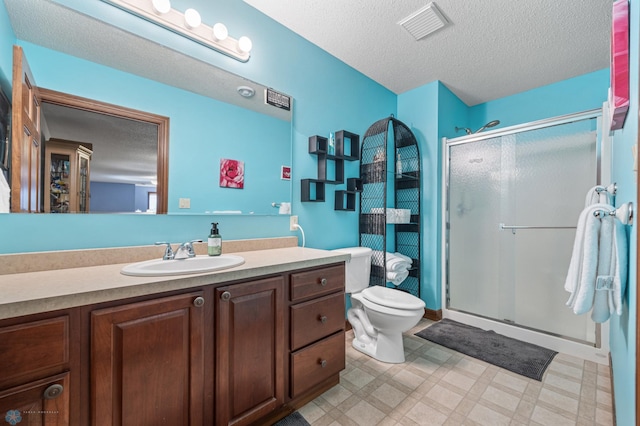 full bath with tile patterned floors, toilet, vanity, a textured ceiling, and a stall shower