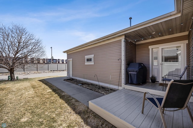 wooden terrace with grilling area, fence, and a yard
